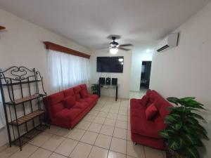 sala de estar con 2 sofás rojos y TV en Central Departamento, en Mazatlán