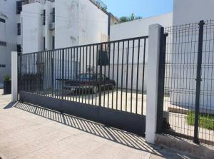 a black metal fence with a car parked behind it at Central Departamento in Mazatlán