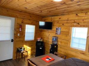 Habitación con pared de madera, mesa y TV. en Canal Cabins en Paw Paw