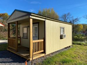 mały żółty budynek z gankiem na trawie w obiekcie Canal Cabins w mieście Paw Paw