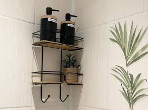 a bathroom rack with three bottles on a wall at Le Royal Cosy - Spacieux T2 - Proche Chantilly, Paris & Astérix in Nogent-sur-Oise