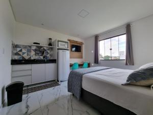 a bedroom with a bed and a kitchen with a refrigerator at Águas de Canto Grande in Bombinhas