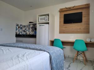 a bedroom with a bed and two green chairs at Águas de Canto Grande in Bombinhas