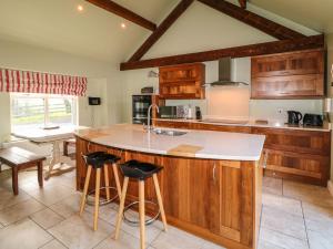 a kitchen with wooden cabinets and a large island with stools at Rosies Cottage in Bushmills