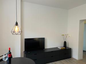 ein Wohnzimmer mit einer schwarzen Kommode mit einem Flachbildfernseher in der Unterkunft Apartmenthaus Buxtehude St -Petri-Platz Studiowohnung 3 in Buxtehude