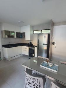 a kitchen with a table and chairs and a refrigerator at Apartamento - Centro Porto de Galinhas in Escada