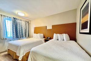 a hotel room with two beds and a window at Days Inn & Suites by Wyndham Arlington Near Six Flags in Arlington