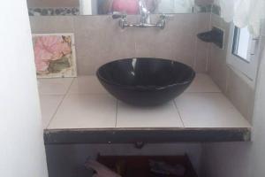 lavabo negro en un mostrador de azulejos en el baño en bellos atardeceres en Villa Las Rosas