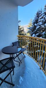 une table et des chaises sur un balcon dans la neige dans l'établissement 1BR Ski In Ski Out Cozy Condo w Pool and Hot Tub by Harmony Whistler, à Whistler