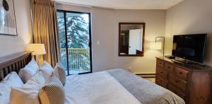 a bedroom with a bed and a television and a window at 1BR Ski In Ski Out Cozy Condo w Pool and Hot Tub by Harmony Whistler in Whistler