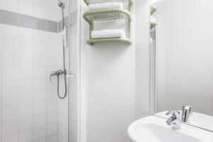 een witte badkamer met een douche en een wastafel bij ibis budget Antwerpen Centraal Station in Antwerpen