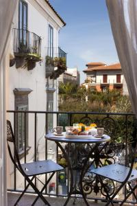 einen Tisch und Stühle auf einem Balkon mit Essen drauf in der Unterkunft AMORE RENTALS - Maison De Charme in Sorrent