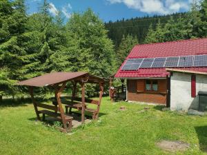 einem Picknicktisch und einem Haus mit Sonnenkollektoren in der Unterkunft Cabana DUY-KAY in Lacul Roşu