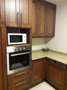 a kitchen with wooden cabinets and a microwave at Casa Rural El Rincón de Diego in La Puebla de Valverde
