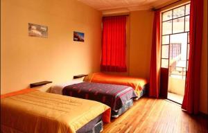 a room with two beds and a window with red curtains at Check Inn Bed and Breakfast in Cuenca