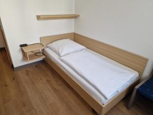 a small bed in a room with a night stand at Hotel Pegasus in Munich