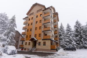 a building in the snow with a car parked in front at Dobro Mesto in Zlatibor