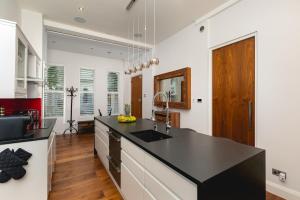 a kitchen with a black counter top and wooden floors at დLUXURY & Spacious Duplex in the Heart of Chelseaდ in London