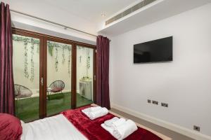 a bedroom with a bed and a tv and a window at დLUXURY & Spacious Duplex in the Heart of Chelseaდ in London