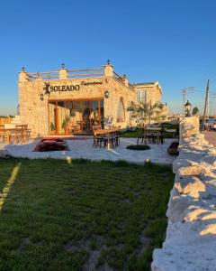 un edificio in pietra con tavoli e tavoli di fronte ad esso di Soleado Cappadocia Hotel a Üçhisar