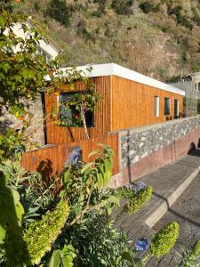 un bâtiment en bois avec une terrasse couverte et une clôture dans l'établissement CASA DA PITANGA, à Jardim do Mar
