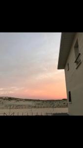 ein Gebäude mit Blick auf den Strand bei Sonnenuntergang in der Unterkunft T2, bord de plage et piscine in Biscarrosse