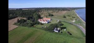 an aerial view of a large house on a field next to the water at Djursland Lystrup Strand in Allingåbro