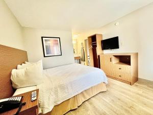 a hotel room with a bed and a television at Days Inn & Suites by Wyndham Arlington Near Six Flags in Arlington