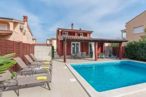 een achtertuin met een zwembad en stoelen en een huis bij Villa Anemona in Fažana