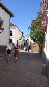 two women walking down a street in an alley at Casa Carmen in Granada