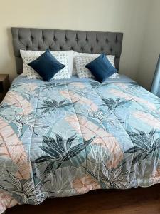 łóżko z kolorową kołdrą i niebieskimi poduszkami w obiekcie Casa Sector Oriente Talca w mieście Talca