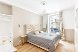 a white bedroom with a bed and a window at SUITE RAPHAEL Tour Eiffel in Paris