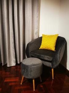 a black chair with a yellow pillow and a stool at The Market Square House in Faro