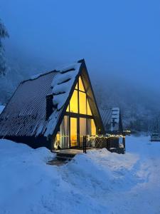 eine Hütte im Schnee mit eingeschaltetem Licht in der Unterkunft Klek 77 Luxury Chalets near Jahorina 