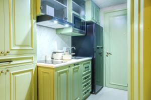 eine Küche mit grünen Schränken und einem Waschbecken in der Unterkunft Apartment Embarcadero Bintaro Suites by Novie Mckenzie in Pondokaren