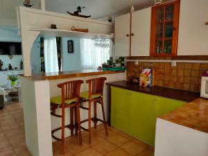 a kitchen with green cabinets and bar stools at Villa La Philomène - entre mer et montagne in Saint-Pierre