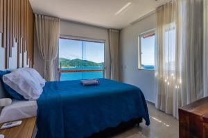 a bedroom with a blue bed and a large window at Villa Orion in Arraial do Cabo