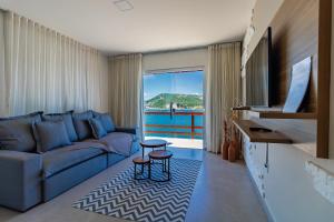 a living room with a blue couch and a large window at Villa Orion in Arraial do Cabo