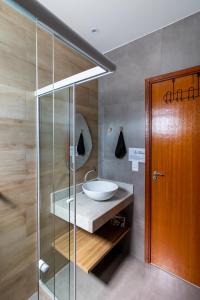 uma casa de banho com um lavatório e uma cabina de duche em vidro. em Villa Orion em Arraial do Cabo