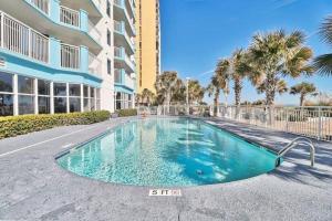 a swimming pool in front of a building with palm trees at Ocean Blue Condos by Coastline Resorts in Myrtle Beach