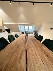 a large wooden table in an office with green chairs at Duplex hyper centre in Liège