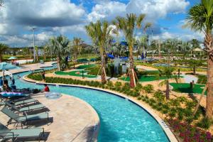 uma piscina num resort com cadeiras e palmeiras em Luxurious 4Bd Home w/ Pool 4983 em Kissimmee
