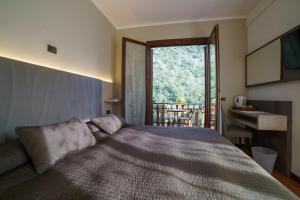 a bedroom with a bed and a large window at Hotel Lago Bin in Rocchetta Nervina