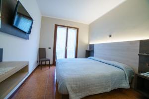 a bedroom with a bed and a television on the wall at Hotel Lago Bin in Rocchetta Nervina