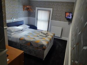 Dormitorio pequeño con cama y TV en Wellington Hotel, en Blackpool