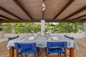 a dining table with blue chairs in a room with a window at Arcadia Retreat Rarotonga in Rarotonga