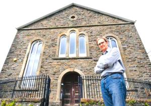 a man standing in front of a church at Afan Forest Bunkhouse-Converted Chapel Sleeps 30 in Glyncorrwg