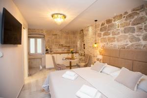a bedroom with a white bed and a stone wall at Guest House Paradise in Split