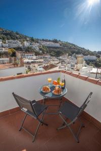 una mesa y 2 sillas en un balcón con comida y bebida en Casa Corbeto 43 en Cómpeta