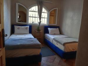 2 camas en una habitación pequeña con ventana en Surf guest house, en Mirleft